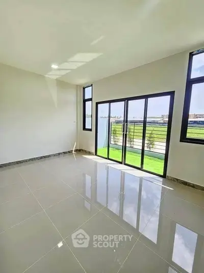 Spacious sunlit room with large windows and garden view, perfect for modern living.