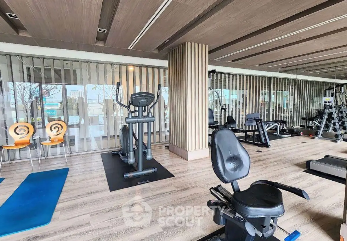 Modern gym with state-of-the-art equipment and stylish wooden flooring in luxury apartment complex.