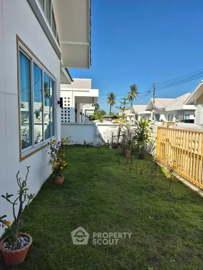 Charming garden view of modern home with lush greenery and clear blue sky.
