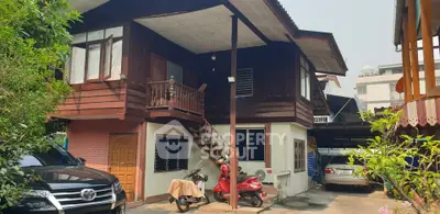 Charming two-story wooden house with outdoor parking and lush greenery, perfect for family living.