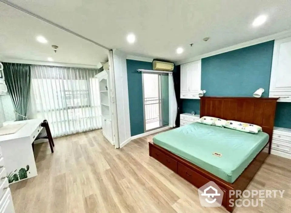 Spacious modern bedroom with balcony and study area, featuring elegant wooden flooring and stylish decor.