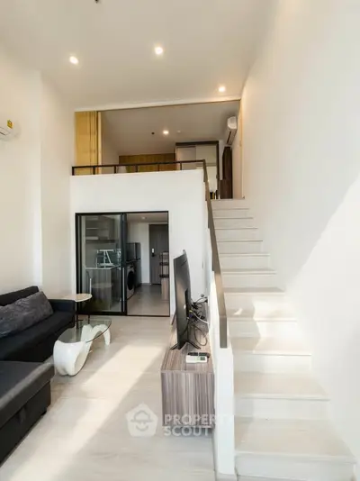 Modern duplex apartment with stylish living area and staircase, featuring sleek design and natural light.