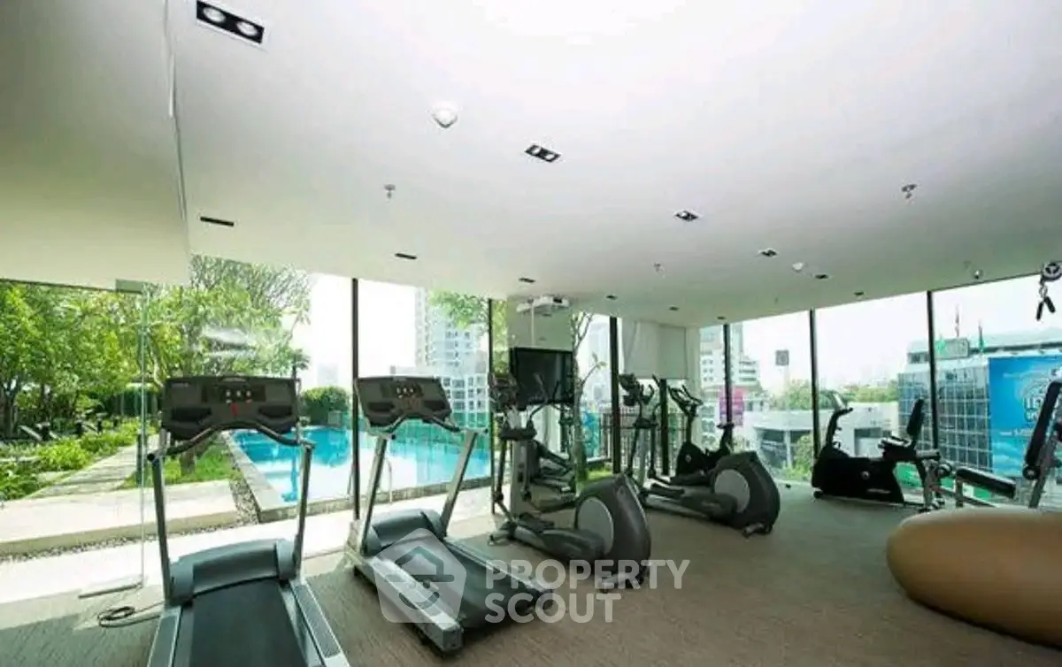 Luxurious gym with modern equipment and pool view in high-rise building