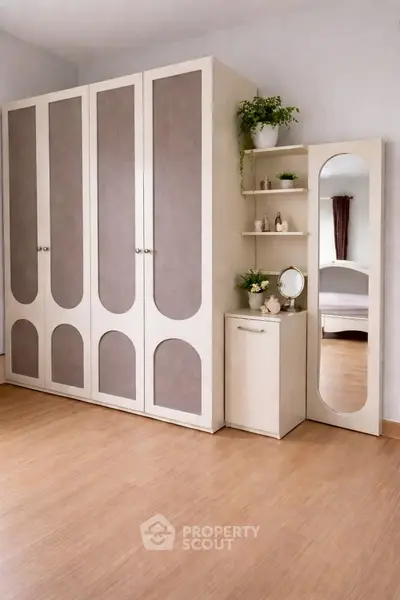 Spacious bedroom with elegant wardrobe and vanity mirror, perfect for modern living.