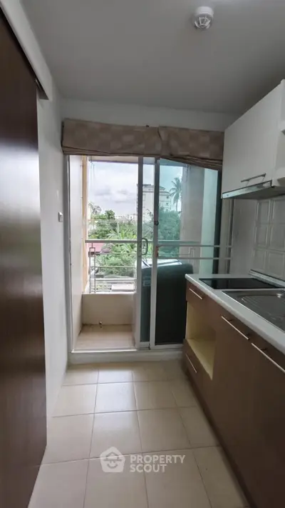 Compact kitchen with balcony access and outdoor view