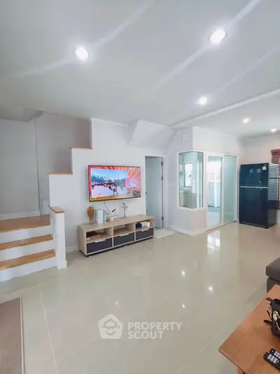 Modern living room with sleek design, staircase, and large TV, perfect for family gatherings.