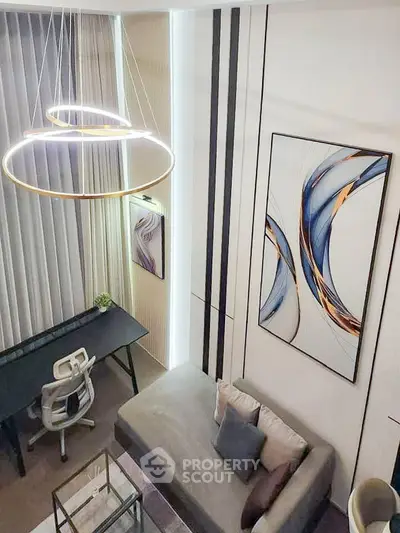 Modern living room with stylish lighting and abstract art, featuring a cozy sofa and sleek workspace.