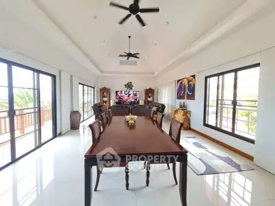 Spacious living room with elegant dining area and large windows offering natural light.