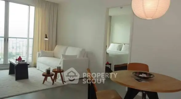 Modern living room with cozy seating and dining area, featuring large windows and natural light.