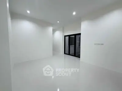 Spacious modern living room with sleek white walls and glossy floor tiles, featuring large glass doors.