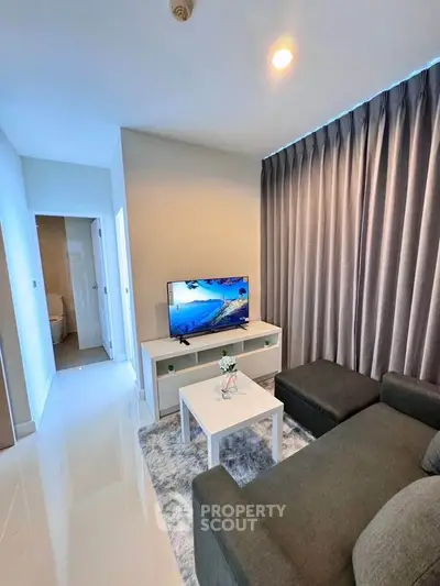 Modern living room with sleek furniture and large TV, perfect for relaxation.