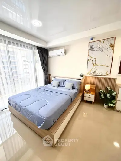 Modern bedroom with stylish decor and large window offering natural light.