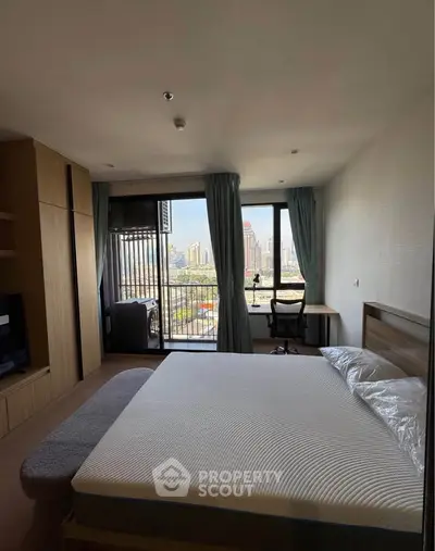 Spacious bedroom with city view and balcony access in modern apartment.
