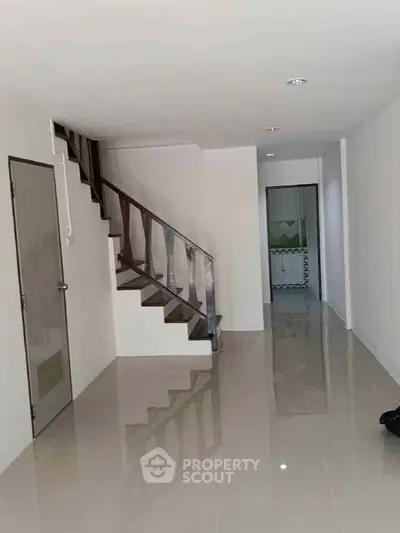 Spacious interior with sleek staircase and glossy tiled flooring, perfect for modern living.