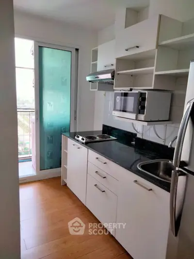 Modern kitchen with sleek appliances and open layout, featuring a balcony view.