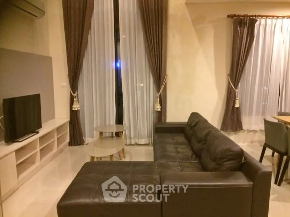 Spacious living room with modern leather sofa and elegant curtains
