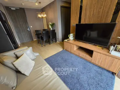 Modern living room with sleek furniture and dining area, featuring a flat-screen TV and elegant decor.
