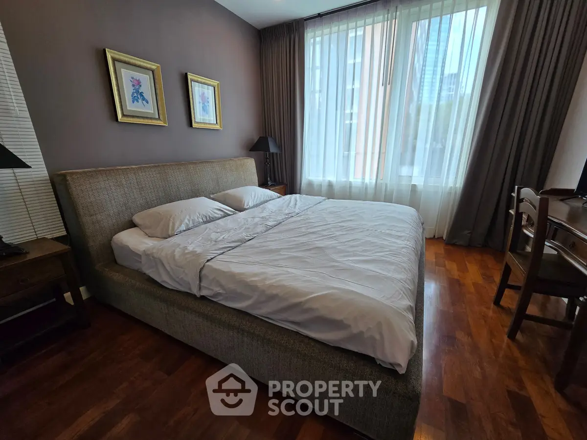 Spacious bedroom with elegant decor and large window offering city views, perfect for relaxation.