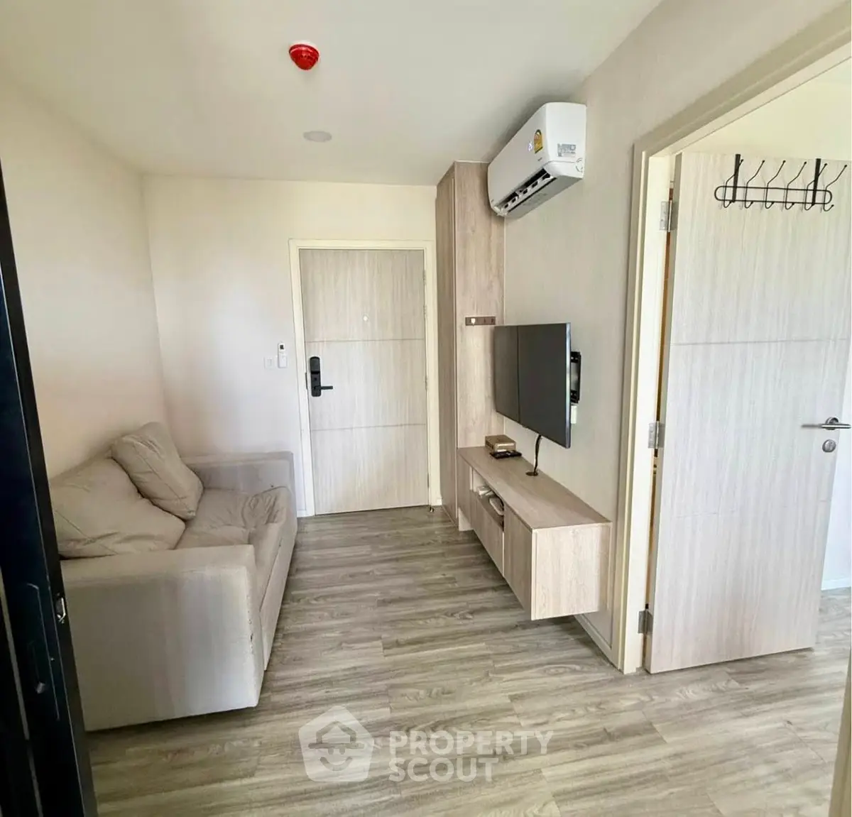 Modern living room with sleek design, featuring a comfortable sofa, wall-mounted TV, and stylish wooden flooring.