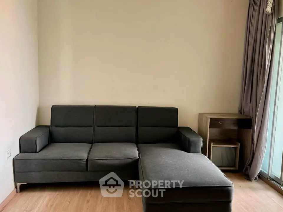 Modern living room with sleek gray sectional sofa and wooden flooring, perfect for cozy relaxation.