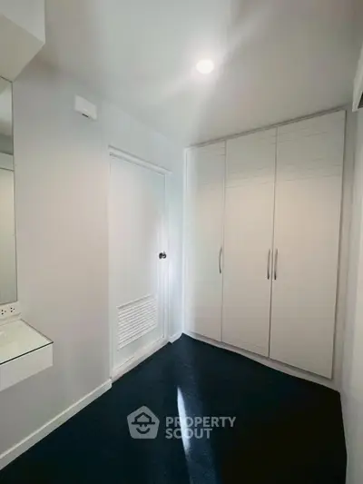 Spacious walk-in closet with sleek white cabinetry and modern lighting.