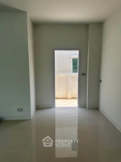 Spacious unfurnished room with glossy tiled floor and natural light, ideal for customization.