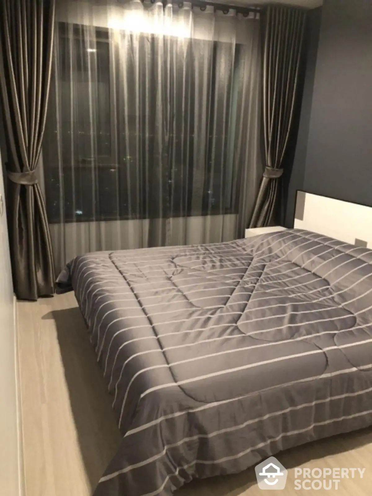 Modern bedroom with stylish curtains and cozy bedding in a high-rise apartment.