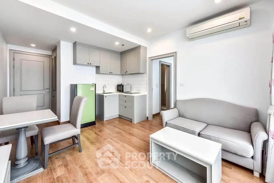 Modern living room with open kitchen, featuring sleek furniture and wooden flooring.