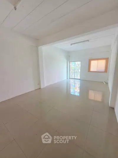 Spacious empty room with tiled flooring and large window, perfect for customization.