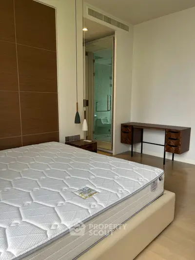 Modern bedroom with stylish furniture and ensuite bathroom in luxury apartment.