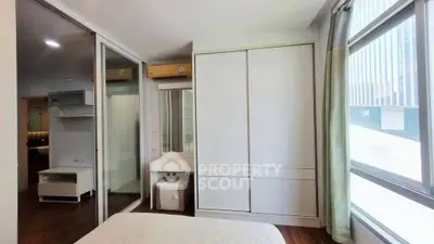 Modern bedroom with large windows and sleek white wardrobe in a stylish apartment.