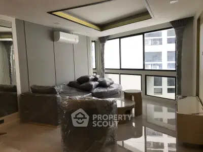 Modern living room with large windows and sleek furniture in a high-rise apartment.