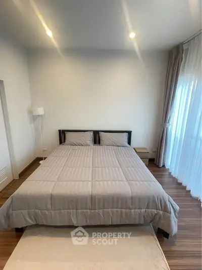 Spacious bedroom with modern decor and large windows for natural light.