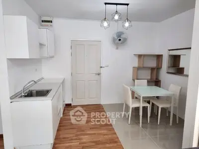 Modern kitchen and dining area with sleek white cabinets and stylish lighting.