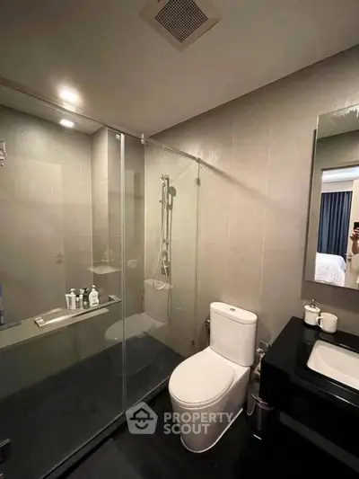Modern bathroom with glass shower and sleek fixtures in contemporary apartment.