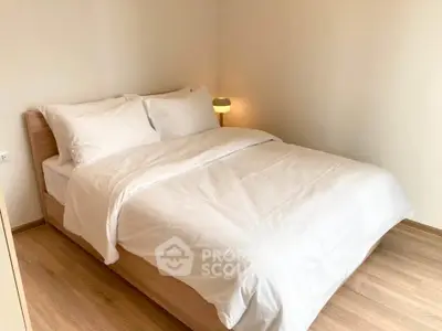 Cozy bedroom with wooden flooring and modern lighting, perfect for relaxation.