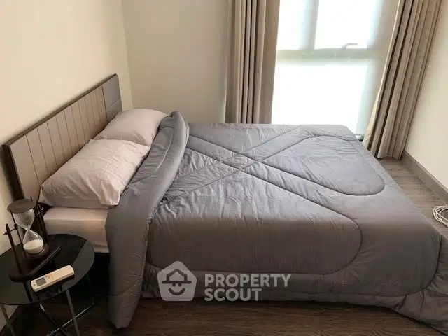 Cozy bedroom with modern decor and natural light, featuring a comfortable bed and stylish side table.