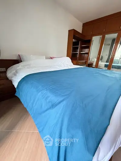 Spacious bedroom with wooden furniture and blue bedding, ideal for relaxation.