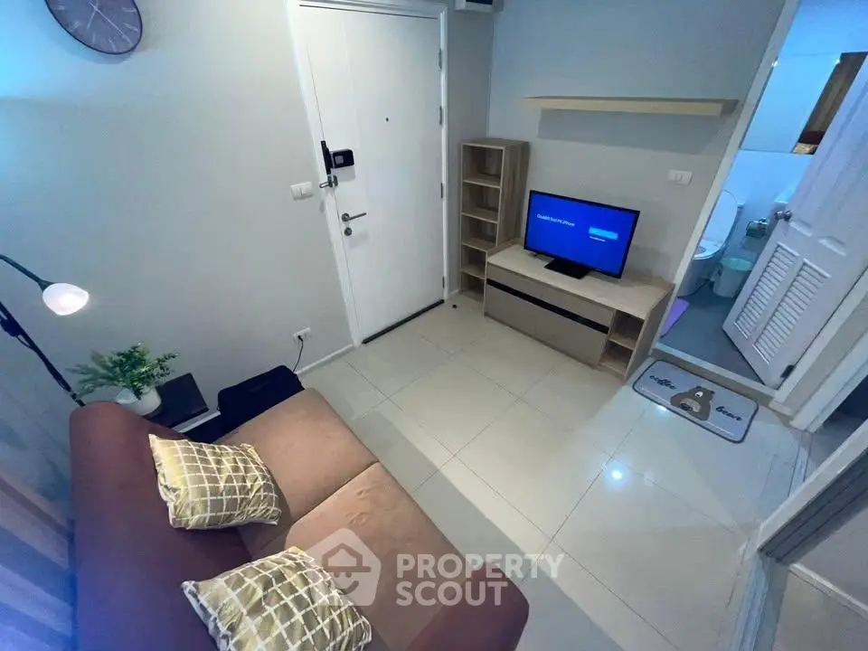 Cozy living room with modern decor and TV, adjacent to a bathroom.