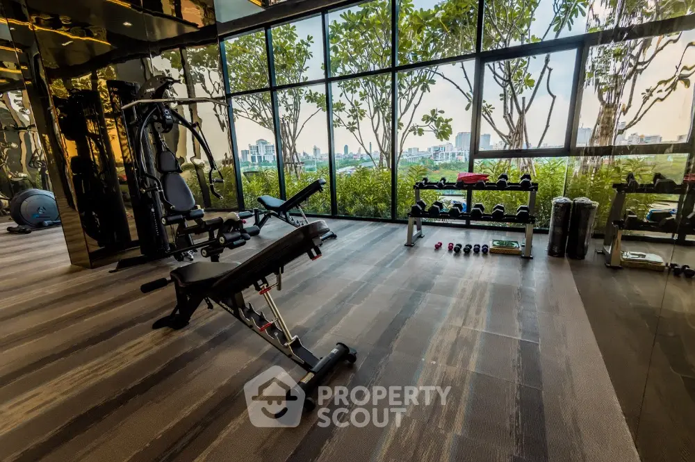 Luxurious gym with modern equipment and stunning city view through large windows.