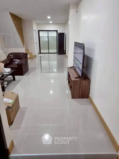 Spacious living room with modern furniture and large TV, perfect for relaxation.