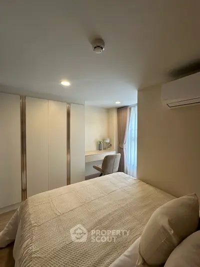 Cozy bedroom with modern decor and natural light, featuring a comfortable bed and workspace.