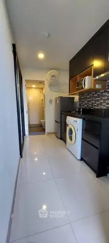 Modern kitchen with sleek cabinets, washing machine, and stylish backsplash in a compact layout.