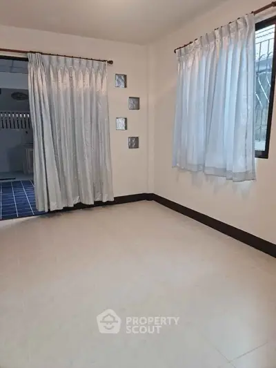 Spacious empty room with tiled floor and large windows, ideal for customization.