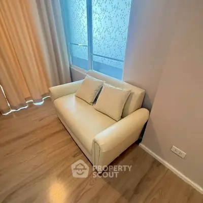 Cozy living room corner with a white sofa and wooden flooring, perfect for relaxation.