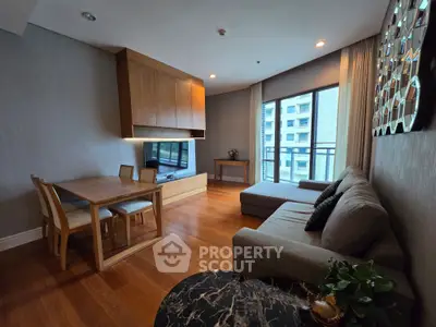 Modern living room with wooden flooring, stylish furniture, and large windows offering natural light.