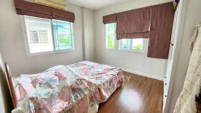 Cozy bedroom with wooden flooring and large windows offering natural light.