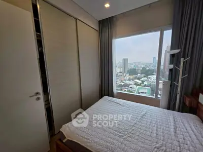 Cozy bedroom with city view and ample natural light, featuring modern wardrobe and elegant decor.