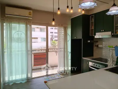 Modern kitchen with open layout and balcony access, featuring stylish lighting and sleek cabinetry.
