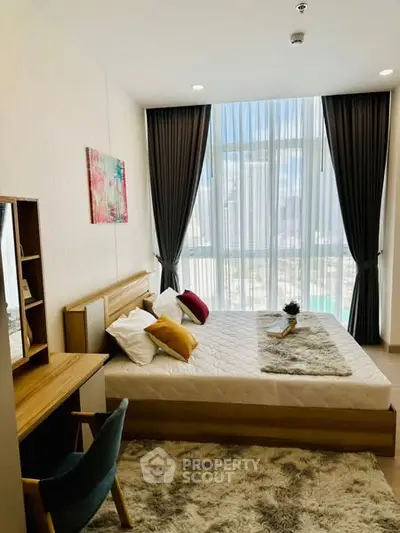 Spacious bedroom with large window and modern decor in high-rise apartment.